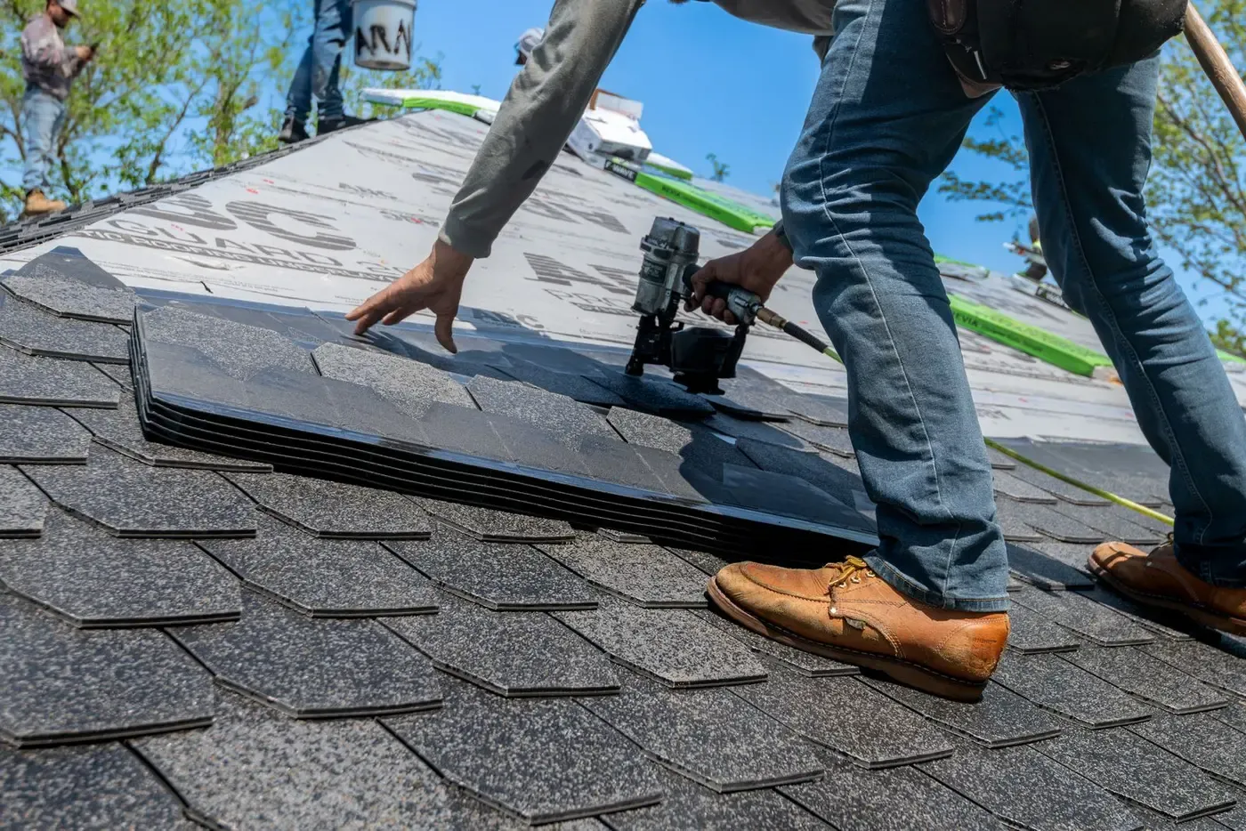 Crew installing a new architectural shingle roof on a brick home